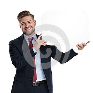 Positive businessman holding a blank speech bubble and laughing