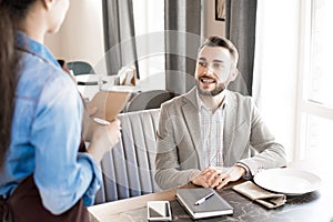 Positive businessman making order in restaurant