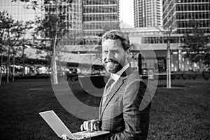 Positive businessman in suit formal wear reading good finance news using mobile wireless internet connection near office
