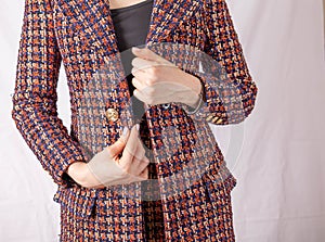 Positive businesswoman fastens button on tweed jacket