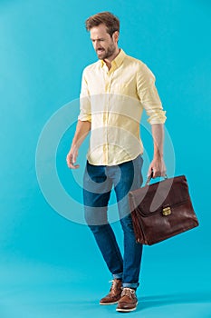 Positive casual man holding his briefcase and smiling