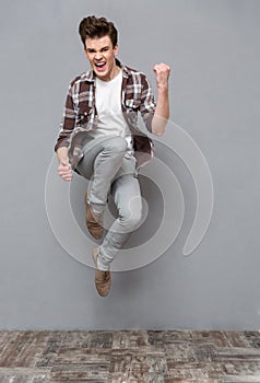 Positive casual young man jumping in the air and smiling