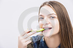 Positive caucasian Teenager Girl Wearing Teeth Braces Biting Avocado