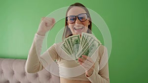 Positive charming woman with glasses, rejoicing, holding money in her hands, showing a loan, recommending a bank