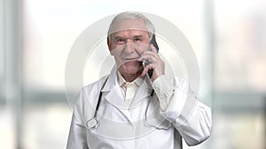Positive cheerful senior doctor talking on the phone.