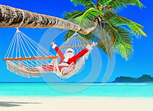 Positive Christmas Santa Claus relax in hammock at palm beach