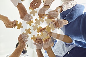 Positive company workers playing with jigsaw puzzle during team building activity