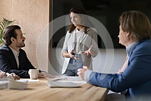 Positive confident business leader woman standing at conference table