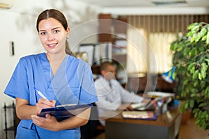 Positive confident young female doctor in a resident's office, writes important notes