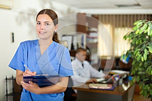 Positive confident young female doctor in a resident's office, writes important notes