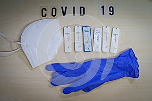 Six positive corona rapid tests lie next to a medical face mask and a blue medical glove