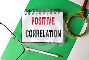 POSITIVE CORRELATION text on notebook on green paper