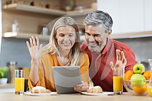 Positive couple enjoying healthy breakfast, using digital tablet