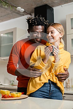 Positive couple laughing while hugging in the kitchen