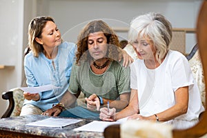 Positive couple and old woman taking notes on the sofa at home