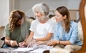 Positive couple and old woman taking notes on the sofa at home