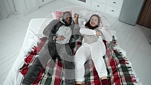 Positive couple in pajamas dancing lying on bed