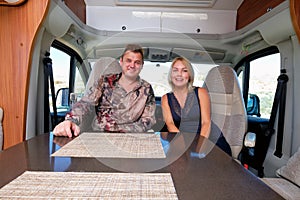 Positive couple sitting inside of recreational vehicle looking at camera