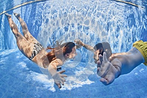 Positive couple swimming underwater in outdoor pool