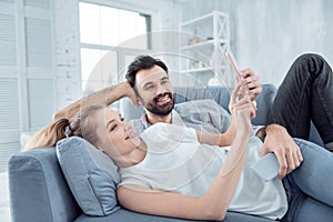 Positive couple taking photos while relaxing together