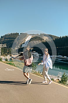 A positive couple of tourists walking along the path of a mountain resort against the backdrop of mountains and lakes. Vertical