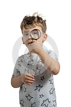 Positive curious schoolboy in casual wear looking at camera through magnifier isolated on white background