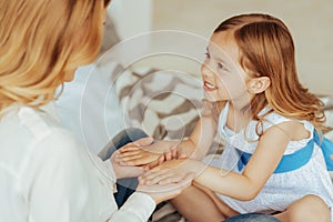 Positive cute girl holding her moms hands