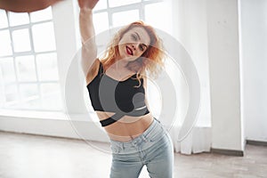 Positive dancer. Attractive redhead woman posing in the spacey room near the window