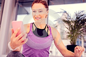 Positive delighted aged woman staring at her gadget