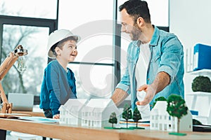 Positive delighted architect pointing at paper houses