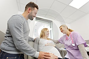Positive doctor talking to pregnant couple in clinic