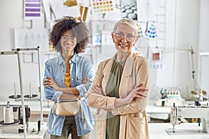 Positive dressmakers pose for camera together in light fashion studio