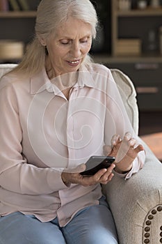 Positive elder woman typing on mobile phone, using online app