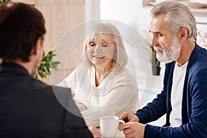 Positive elderly couple having conversation with advisor at home