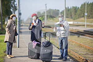 Positive elderly seniors people with face masks waiting for train before traveling during  COVID-19 pandemic