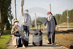 Positive elderly seniors people with face masks waiting train before traveling duringa pandemic