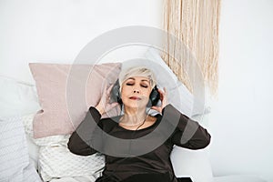 Positive elderly woman listening to music. The older generation and new technologies.