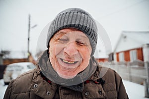 Only positive emotions. Close-up portrait of delighted old man in warm clothes is standing outdoors and laughing