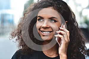 Positive emotions. Lifestyle concept. Close up of young mixed race woman use a phone