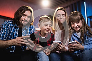 Positive family of four playing games on smartphones