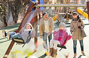 Positive family spending time at children swings