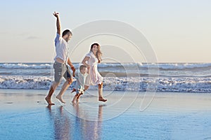 Positive family running along sea edge on the beach
