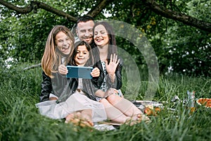 Positive family taking selfie on smartphone on fresh air