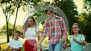 Positive family walking on street. Cheerful kids and parents laughing outdoors