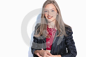 Positive fashion model smiling and wearing leather jacket while standing