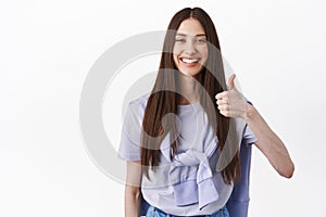 Positive feedback. Smiling brunette woman showing thumb up, nod in approval, support good choice, praise great work