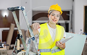 Positive female civil engineer taking notes while checking construction site