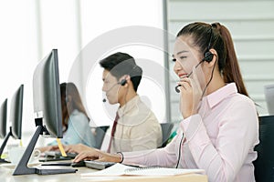 Positive female customer services agent with headset working in call center