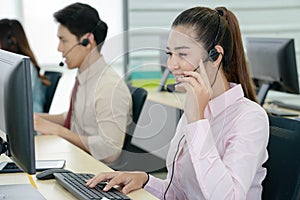 Positive female customer services agent with headset working in call center