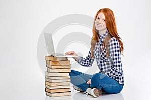 Positive female put laptop on books and using it